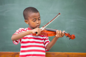 health benefits of music pictured here is a Cute pupil playing violin in classroom at the elementary school