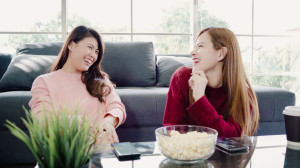 words matter Asian women using smartphone and eating popcorn in living room a