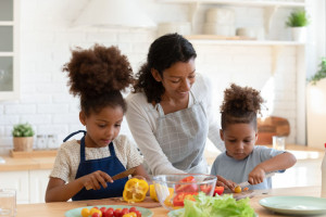 eating together as a family - Loving biracial mom teach little kids cooking in kitchen 